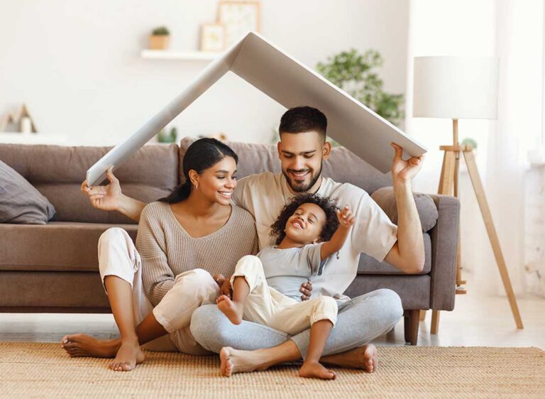 A young couple and a real estate agent touring the interior of a sunlit residential home.