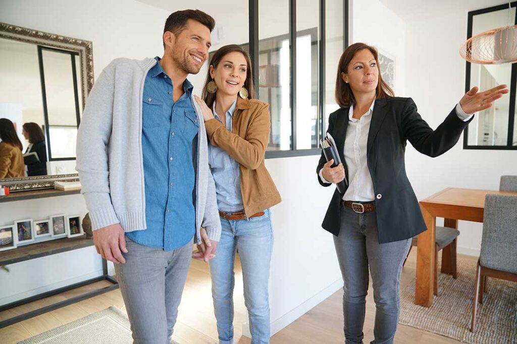 A couple sits at a table with a real estate attorney, reviewing home purchase paperwork and signing documents.