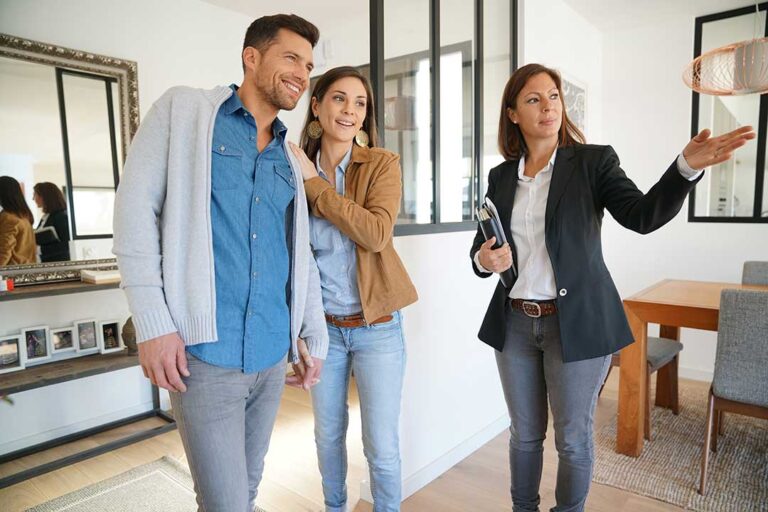 A couple sits at a table with a real estate attorney, reviewing home purchase paperwork and signing documents.